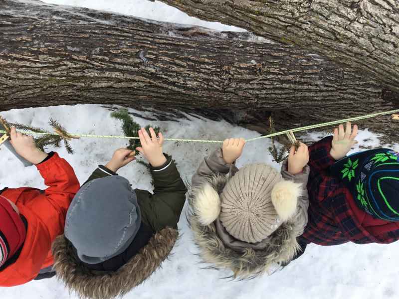 children hanging clothspins on a rope outdoors in the winter